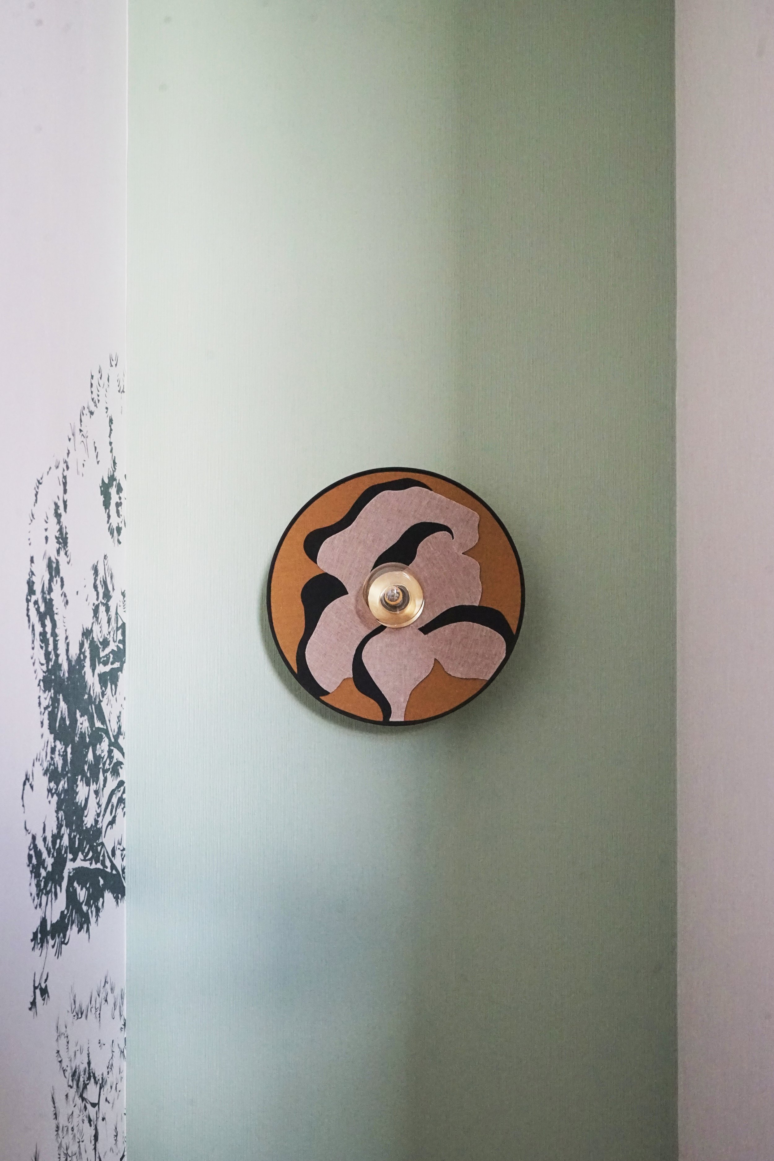 Applique murale contemporaine installée sur un revêtement mural aux teintes douces dans un projet de décoration d'un appartement neuf en Alsace.