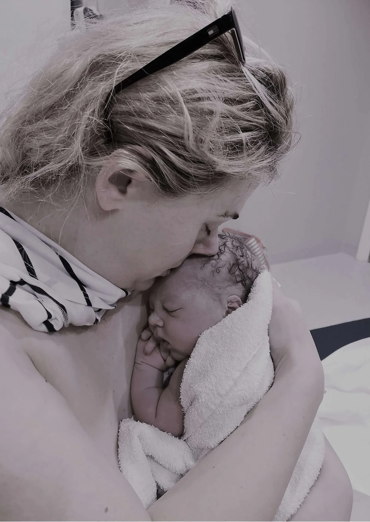 Smiling mother holding newborn in birth pool after a physiological home water birth in the UK.