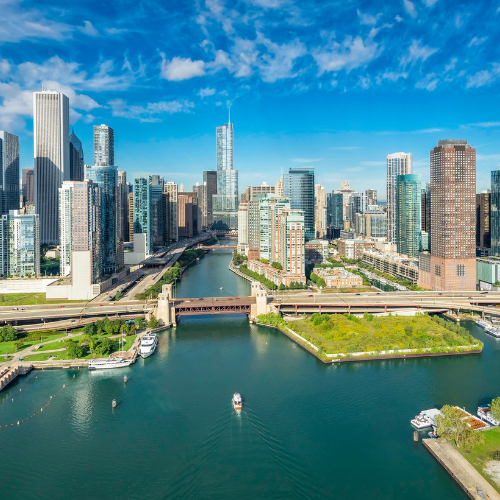 Chicago skyline with river, bridges, and boats under a clear blue sky