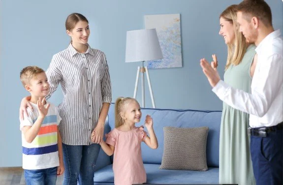 Parents waving goodbye to two children and a nanny