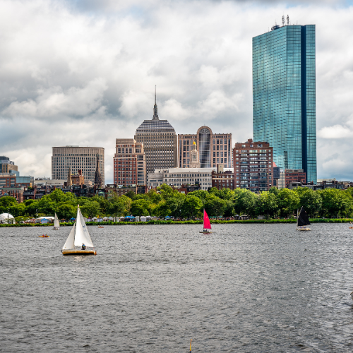 Boston skyline with sailboats on the Charles River under a cloudy sky