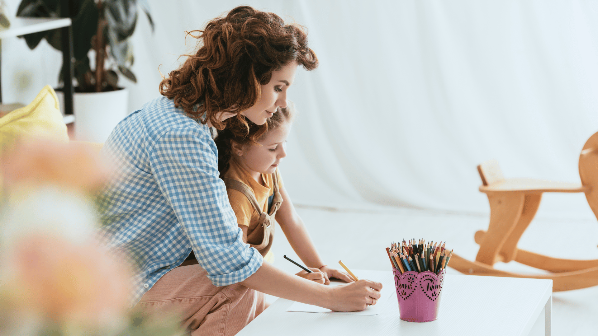 Nanny and child sitting and drawing with pencils