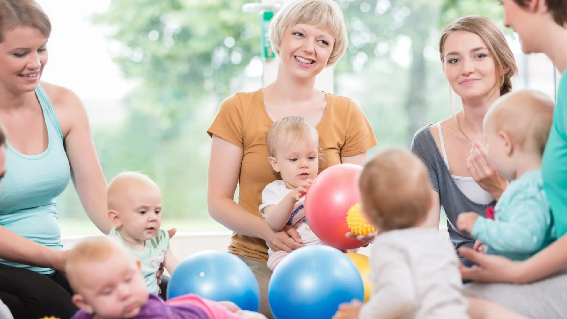 A group of mothers and babies playing with colored balls at a mommy and me class