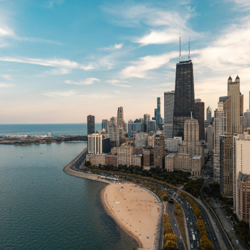 Chicago skyline along Lake Michigan with beach and waterfront under a partly cloudy sky