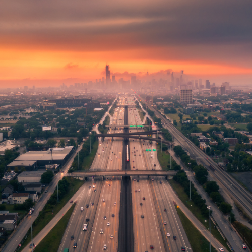 Aerial view of a highway leading into Chicago with the city skyline in the distance at sunrise