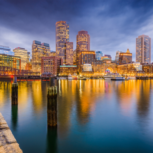 Boston waterfront skyline at night with illuminated buildings and reflections on the water