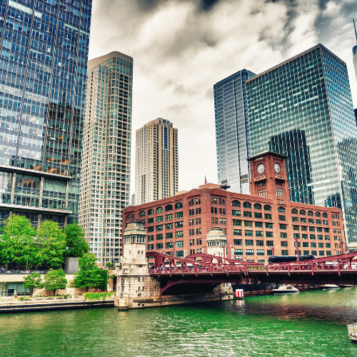 Chicago River with a red bridge and historic clock tower building surrounded by modern skyscrapers