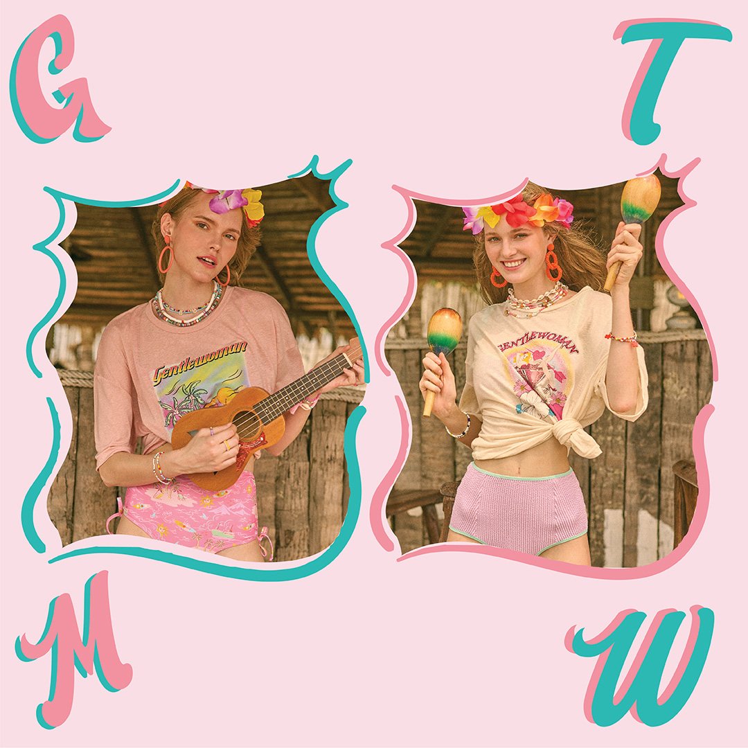 Two young women dressed in colorful matching summer outfits with floral accessories, holding maracas, standing outdoors against a rustic wooden background.