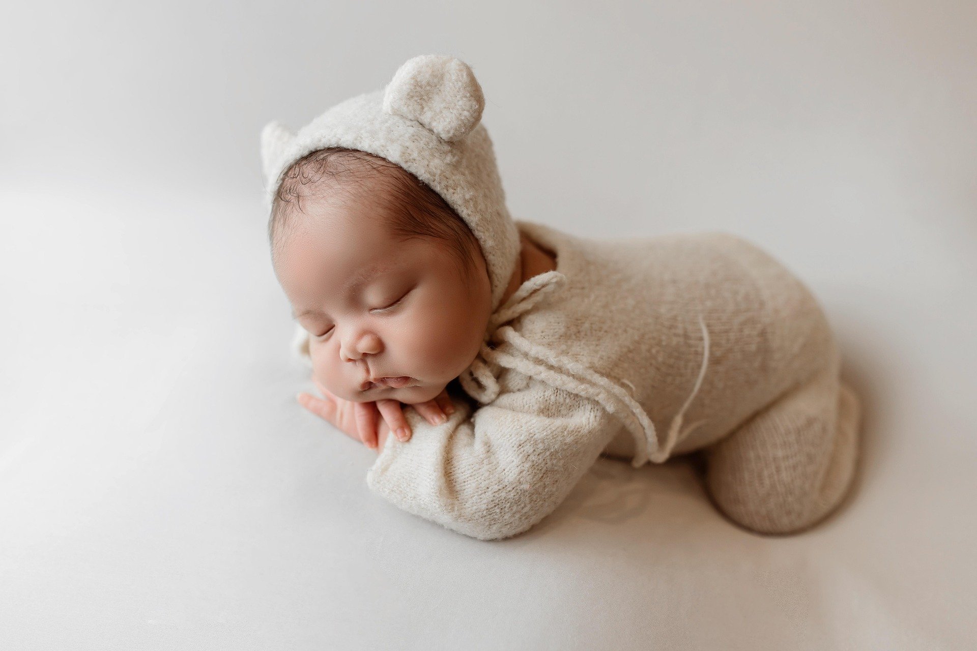 Sleeping baby in beige knit bear ear bonnet and footed sleeper Gentle Night