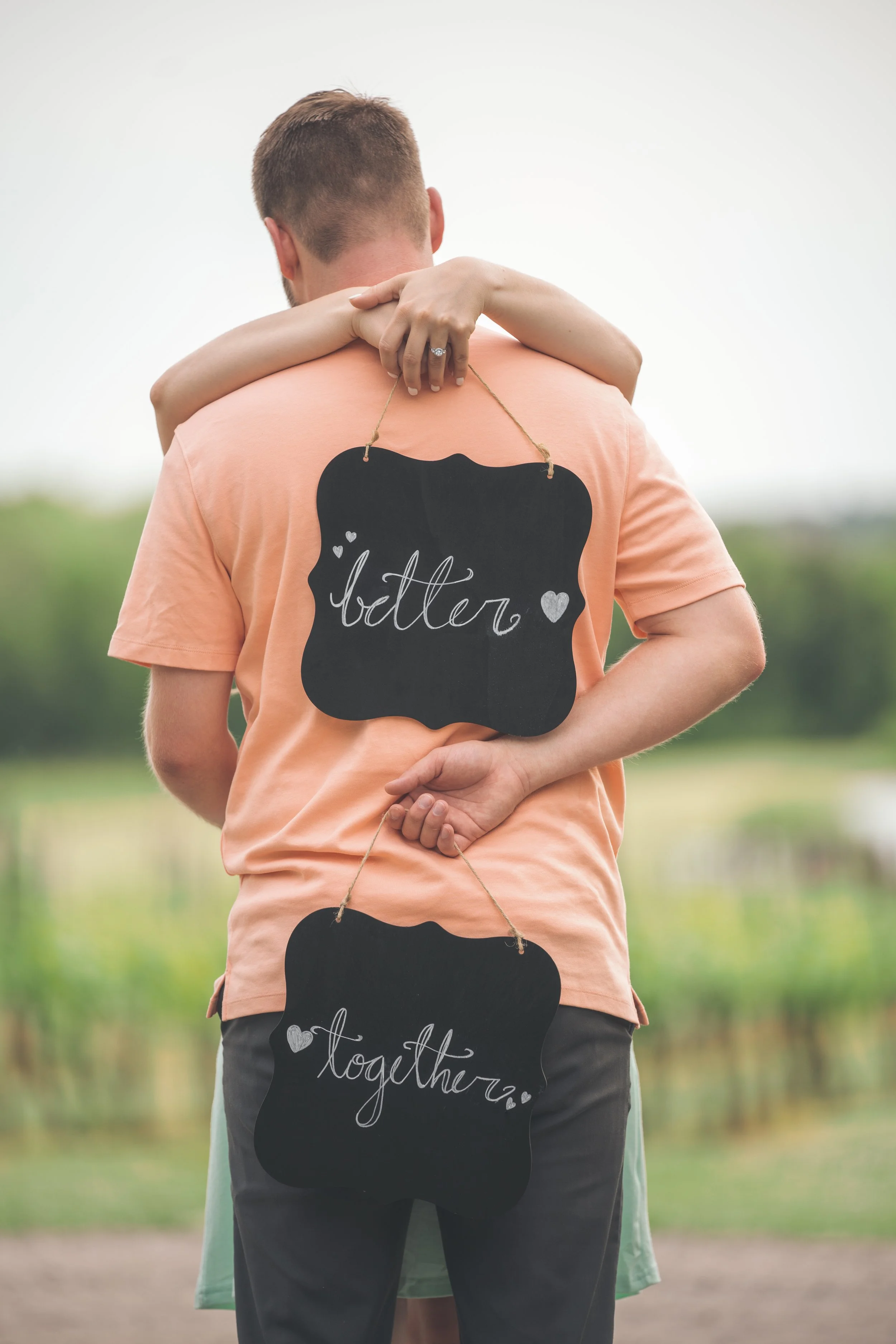 Couple embracing with chalkboards saying 'better together'