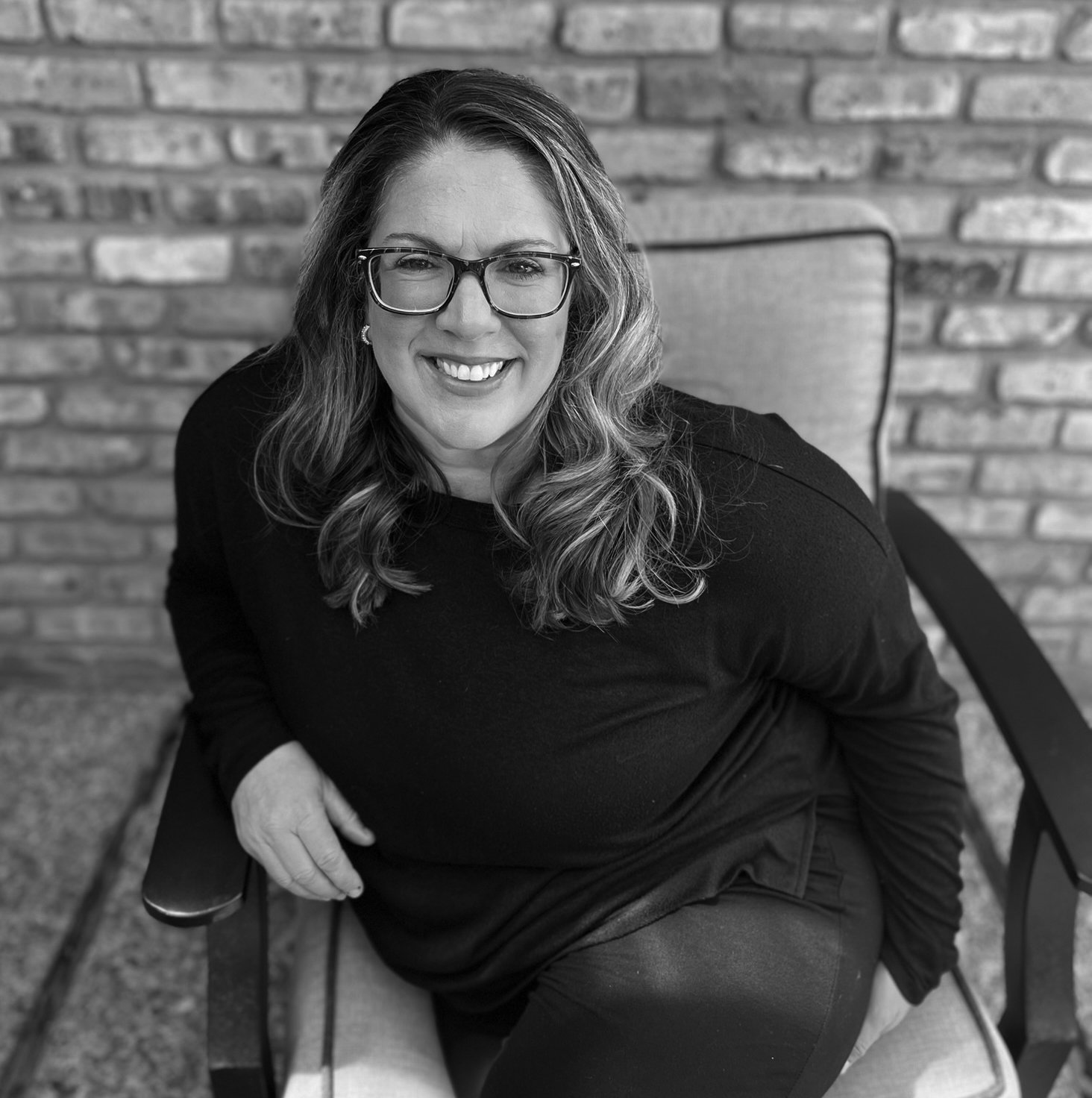 April Capochino Myers seated against a brick wall