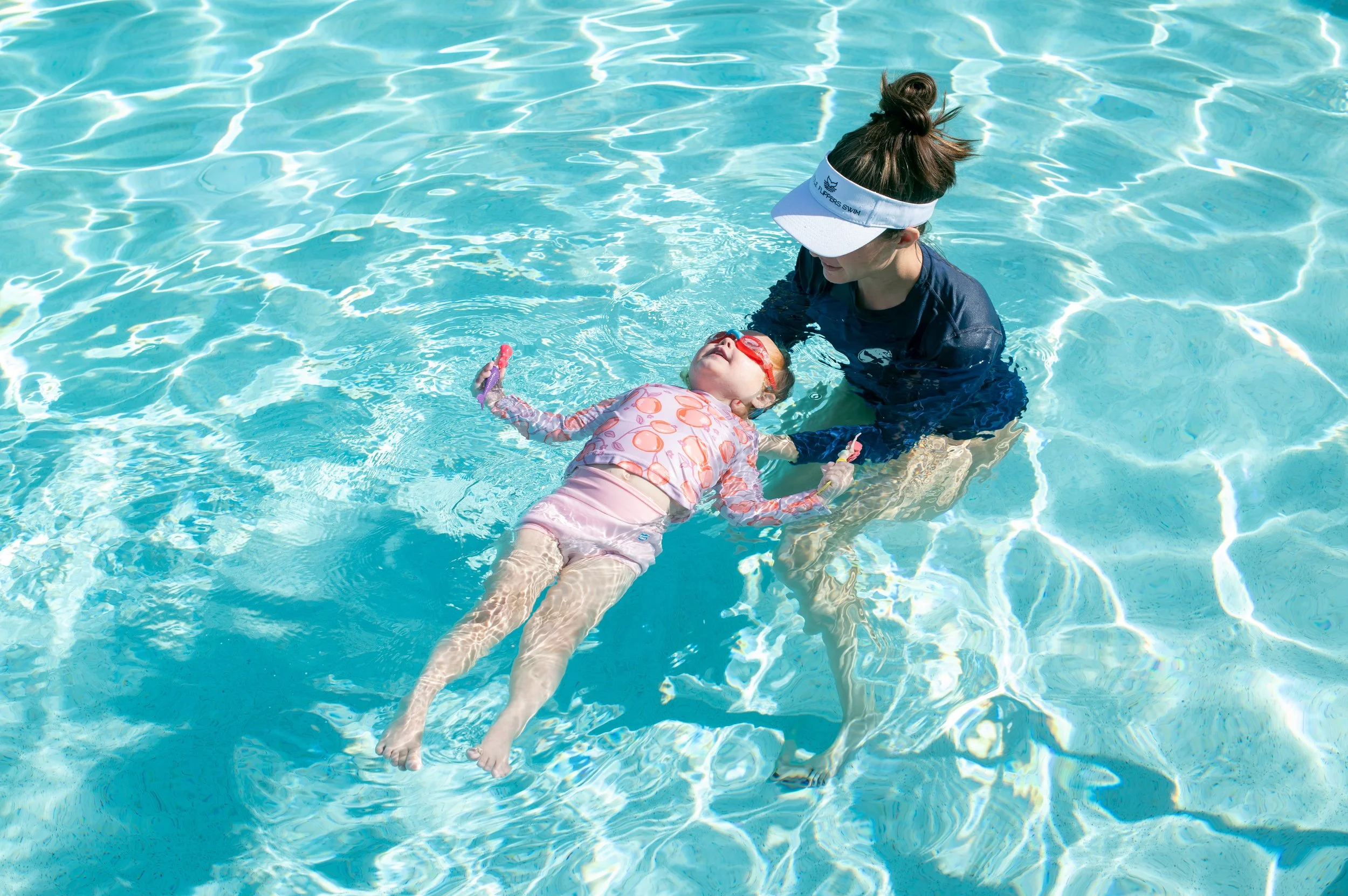 Child learning to swim, assisted by an expert Swim instructor at Little Flippers Swim in a swimming pool