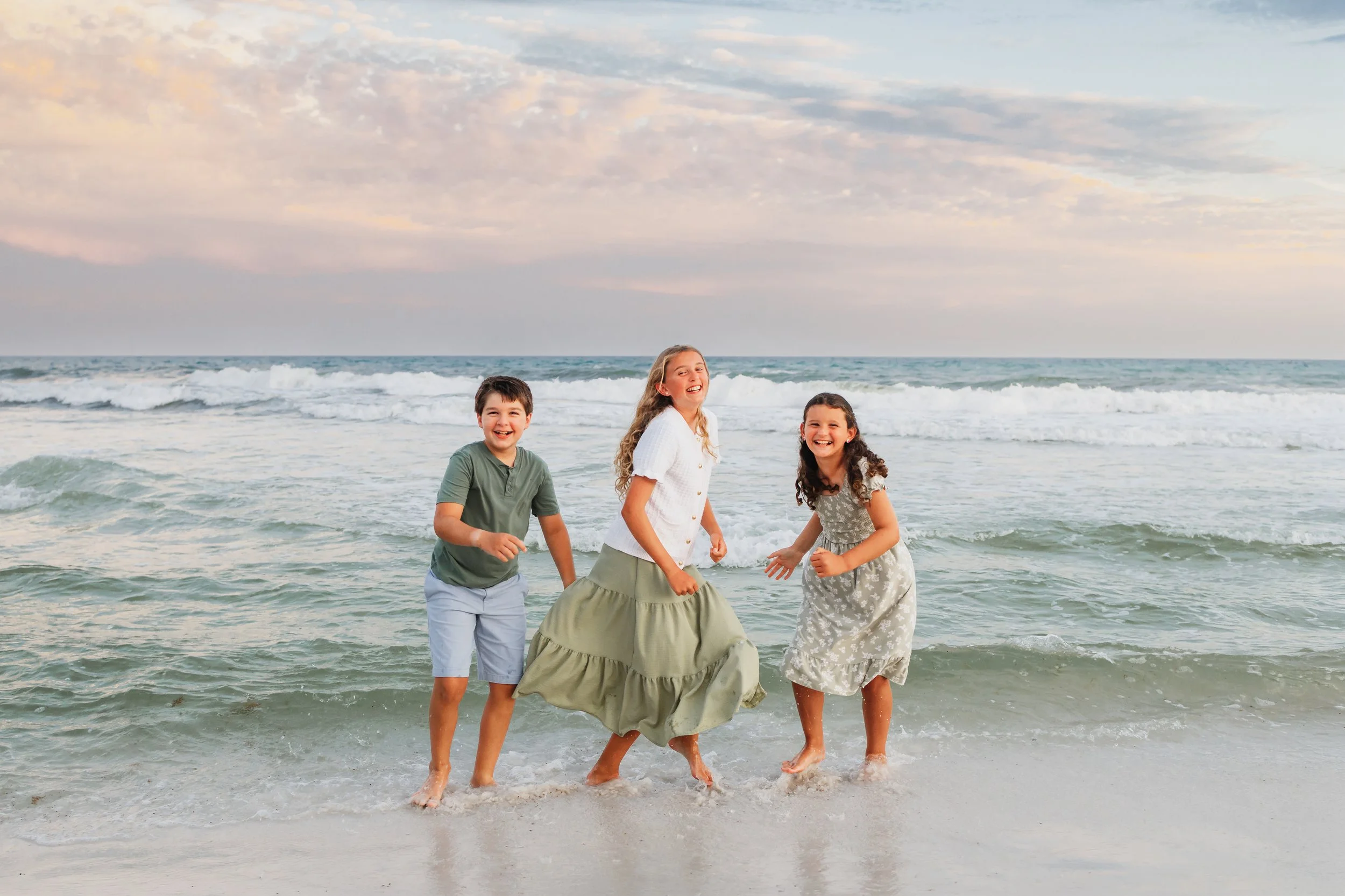 Three children jumping over the waves at Pensacola Beach during a session with Kristen Coberly Photography