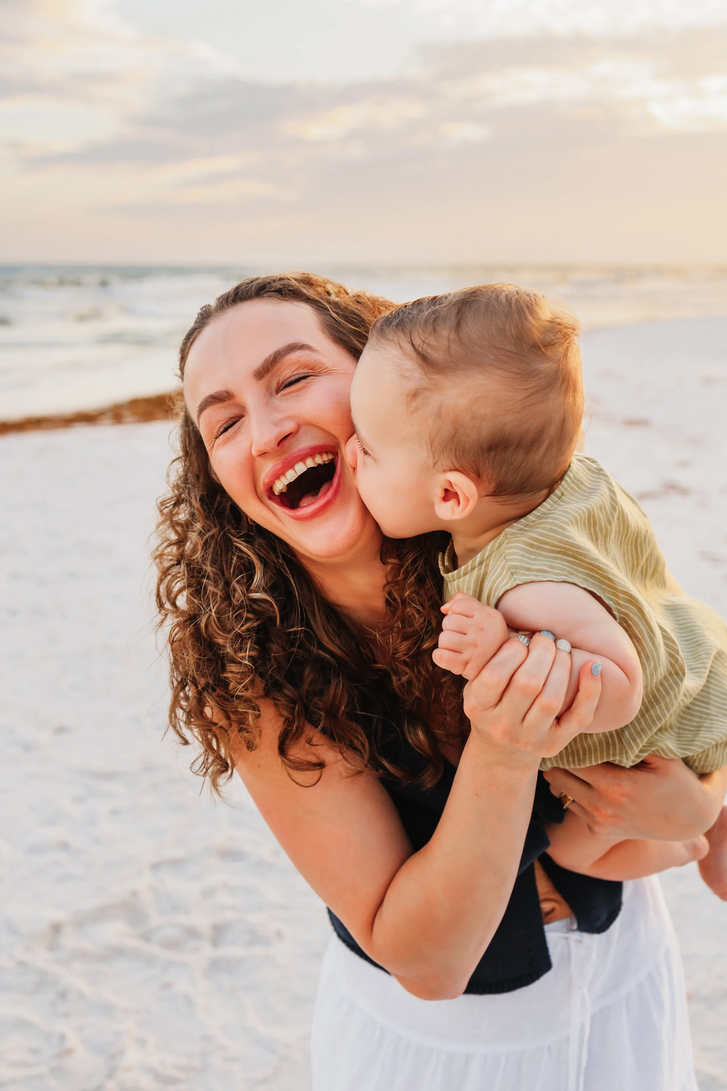 Baby gives his mom sloppy kisses on the check during a photo session on Pensacola Beach with Kristen Coberly Photography