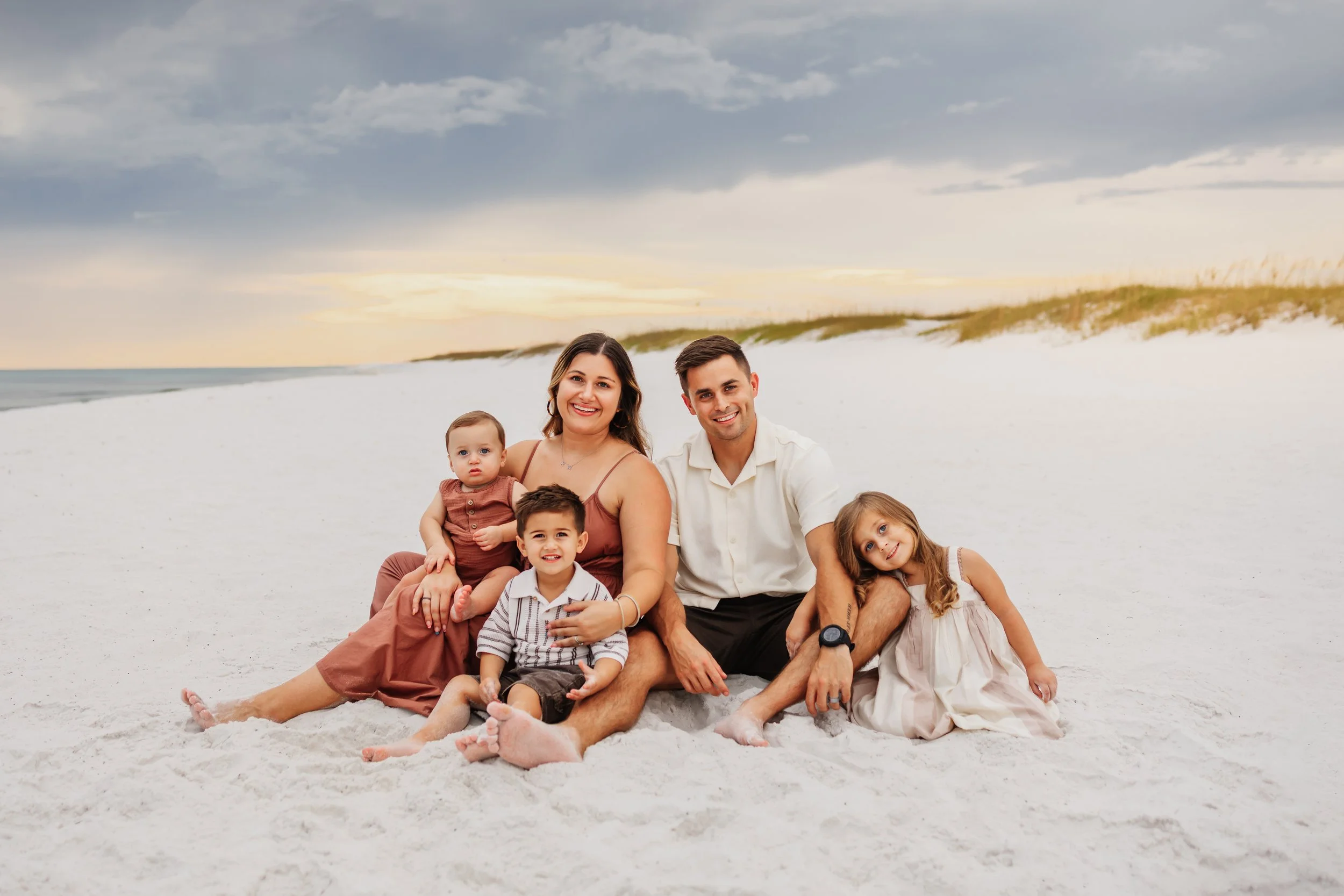 A young family with three toddlers smile on Pensacola Beach during a Pensacola Beach Photography Session with Kristen Coberly Photography
