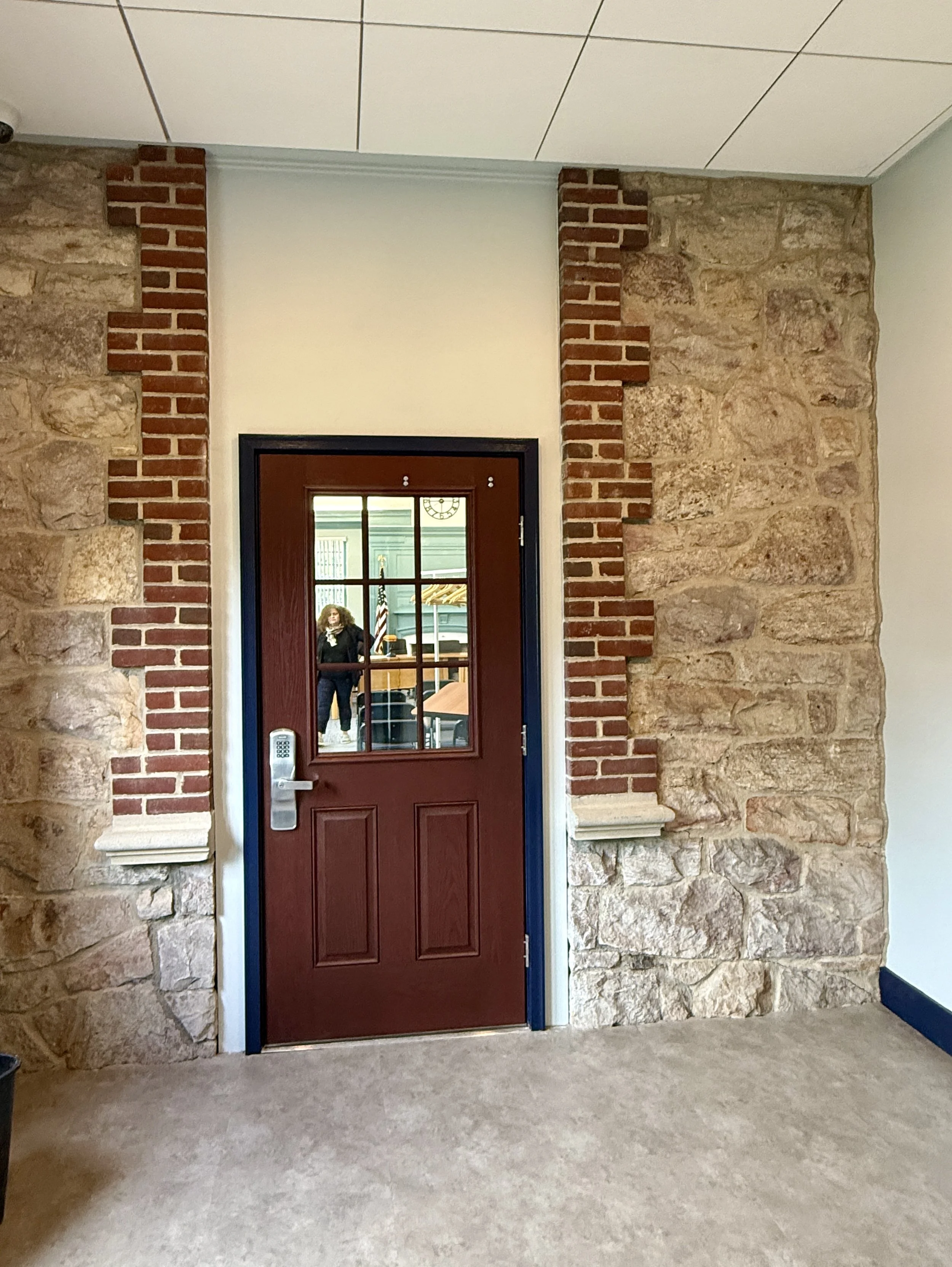 brick red door with window flanked by brick accents and stone wall