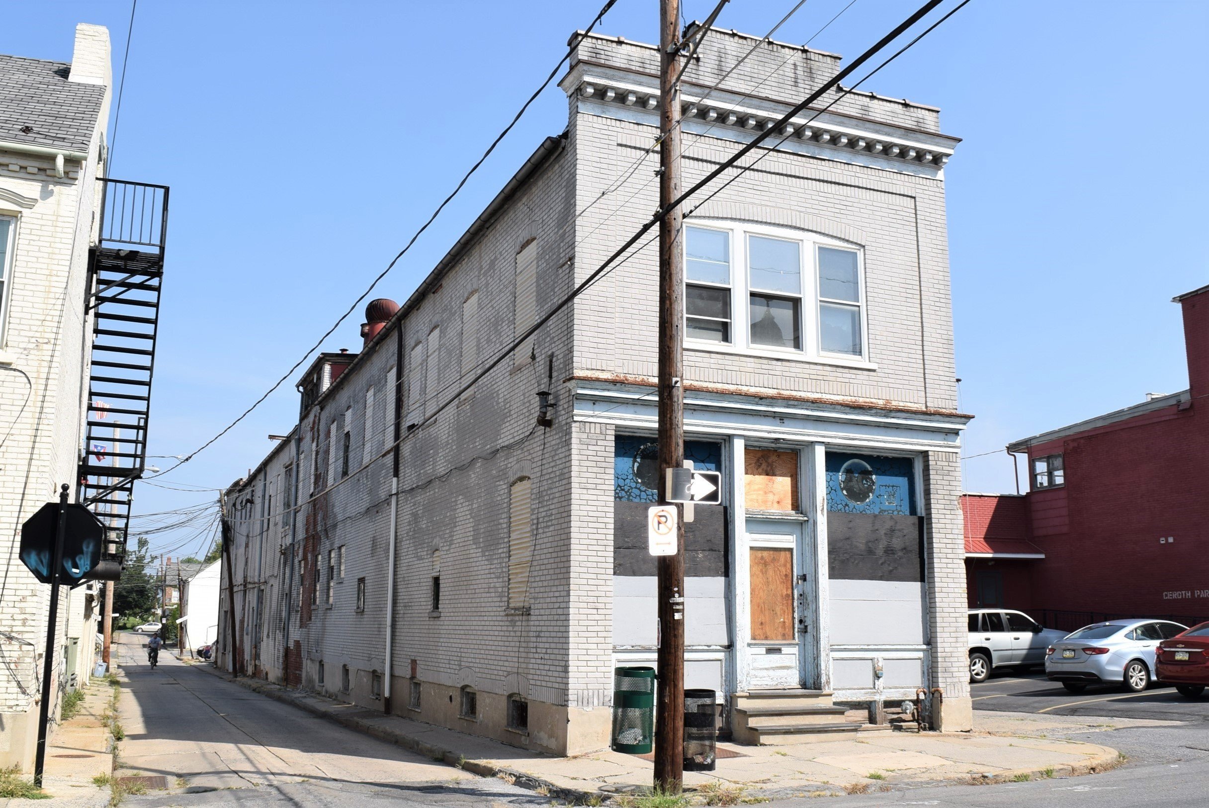 Nnarrow, two-story painted brick building with boarded windows and doors