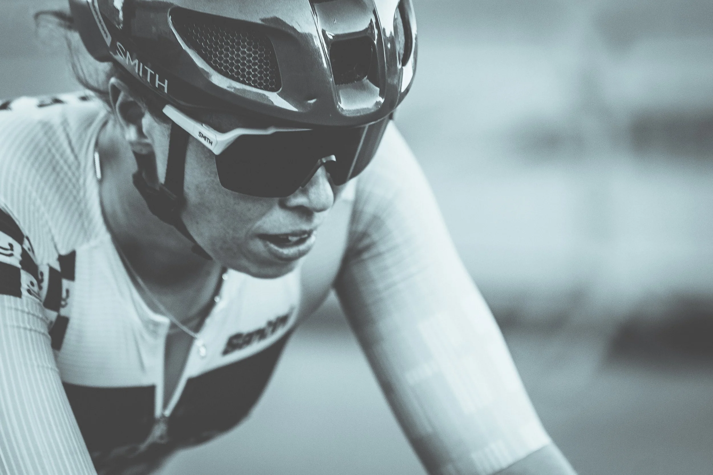 A cyclist wearing a helmet and sunglasses during a race, focusing intently.