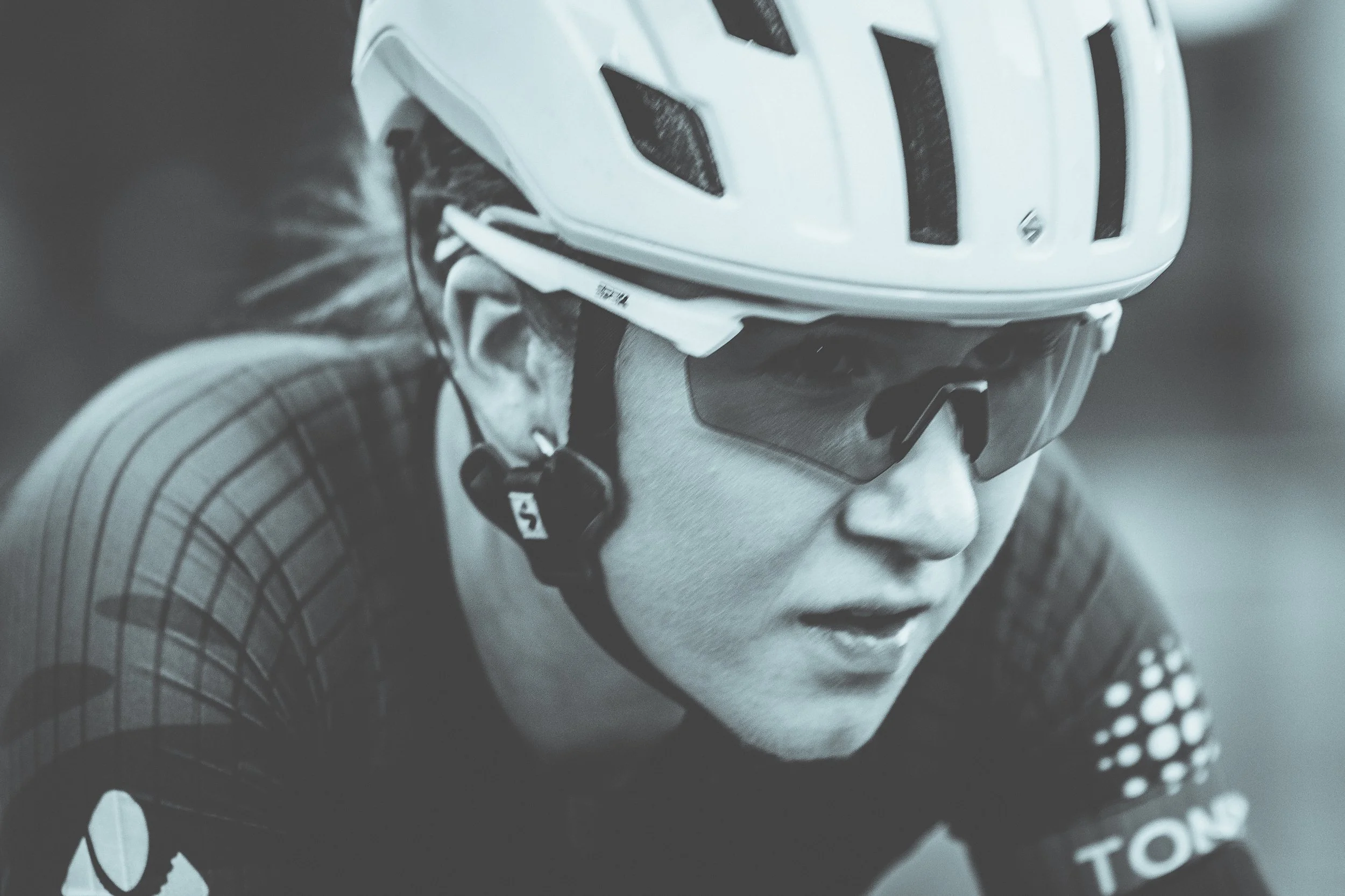 Close-up of a cyclist wearing a helmet and sunglasses, focused on riding.