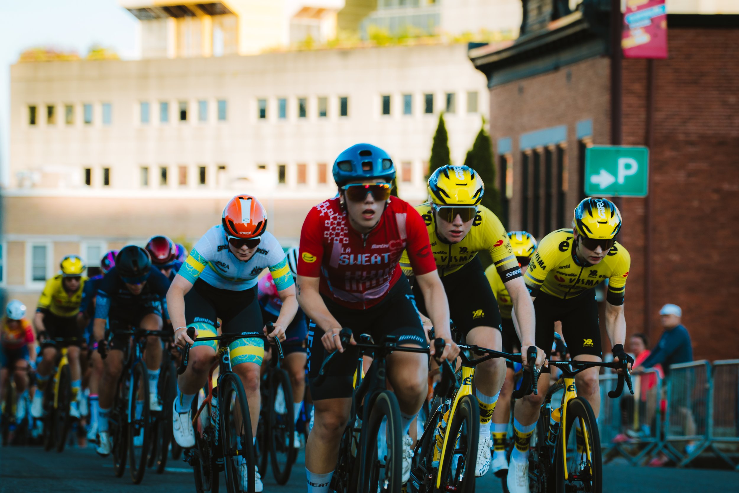 Cyclists racing in a city street, wearing helmets and colorful jerseys.