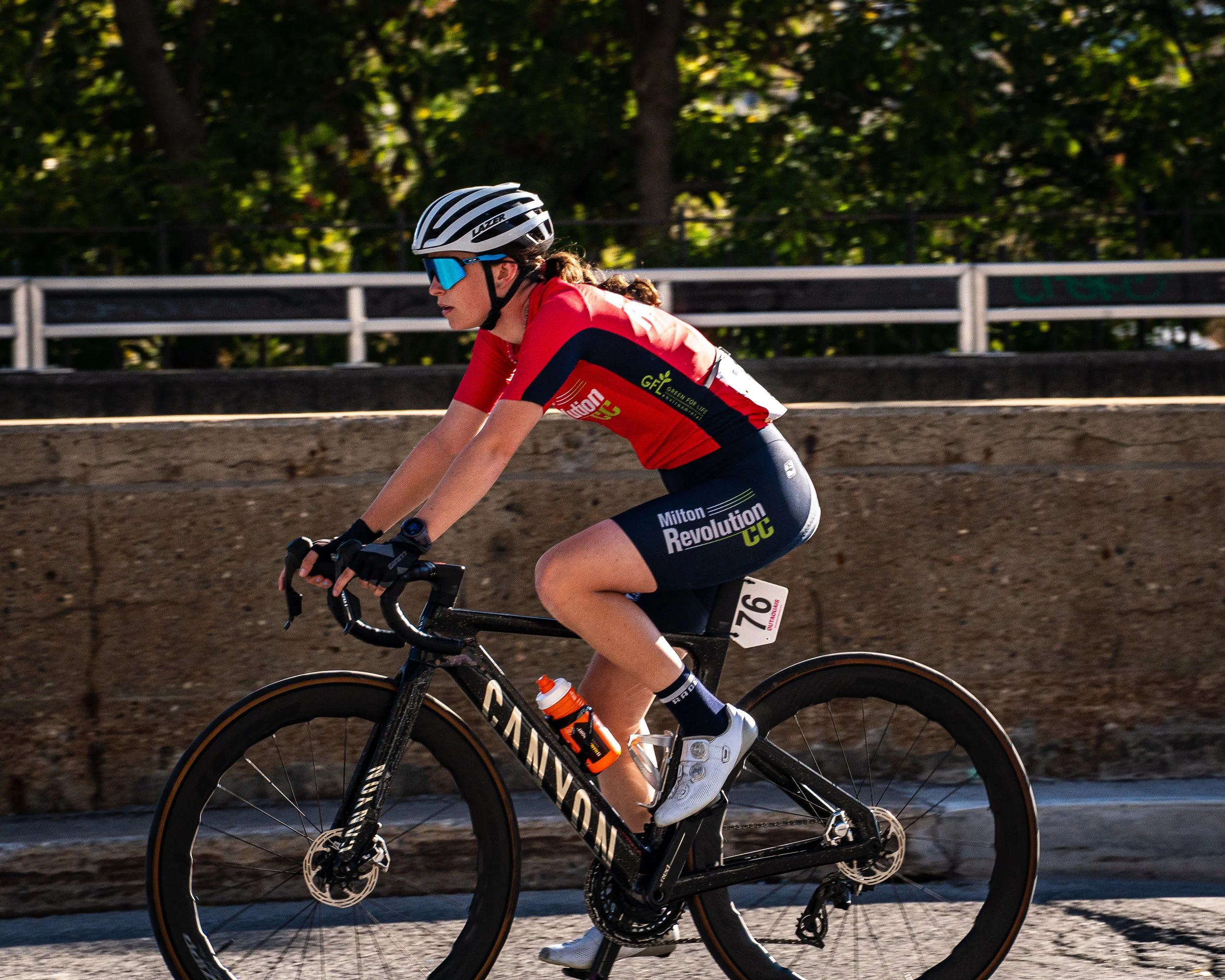 A female cyclist in a red and black outfit riding a black Cannondale bike during a race.