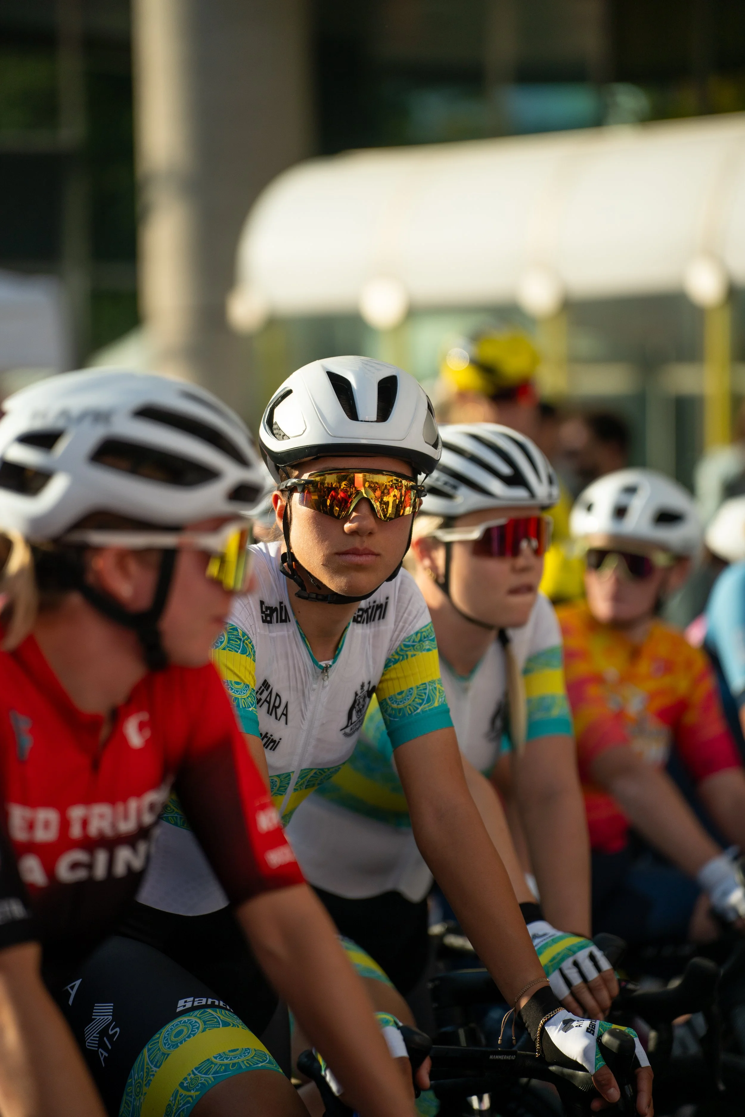 Group of female cyclists wearing helmets and sunglasses, preparing for a race