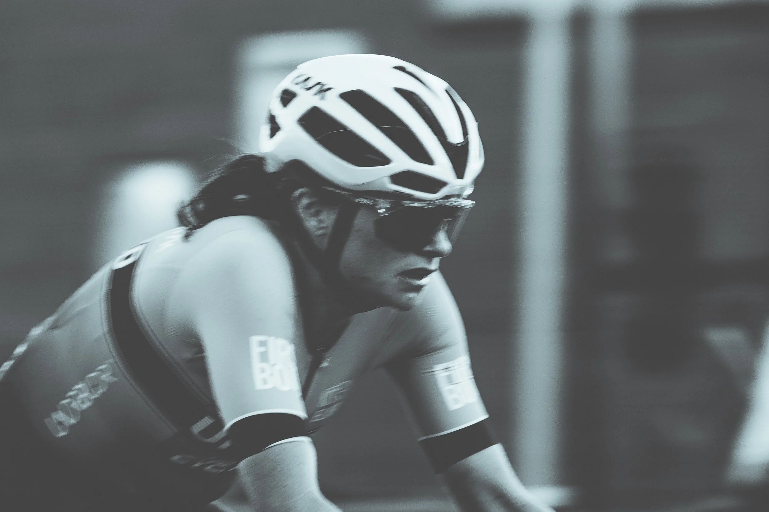 A female cyclist wearing a helmet and sunglasses, focused on riding.