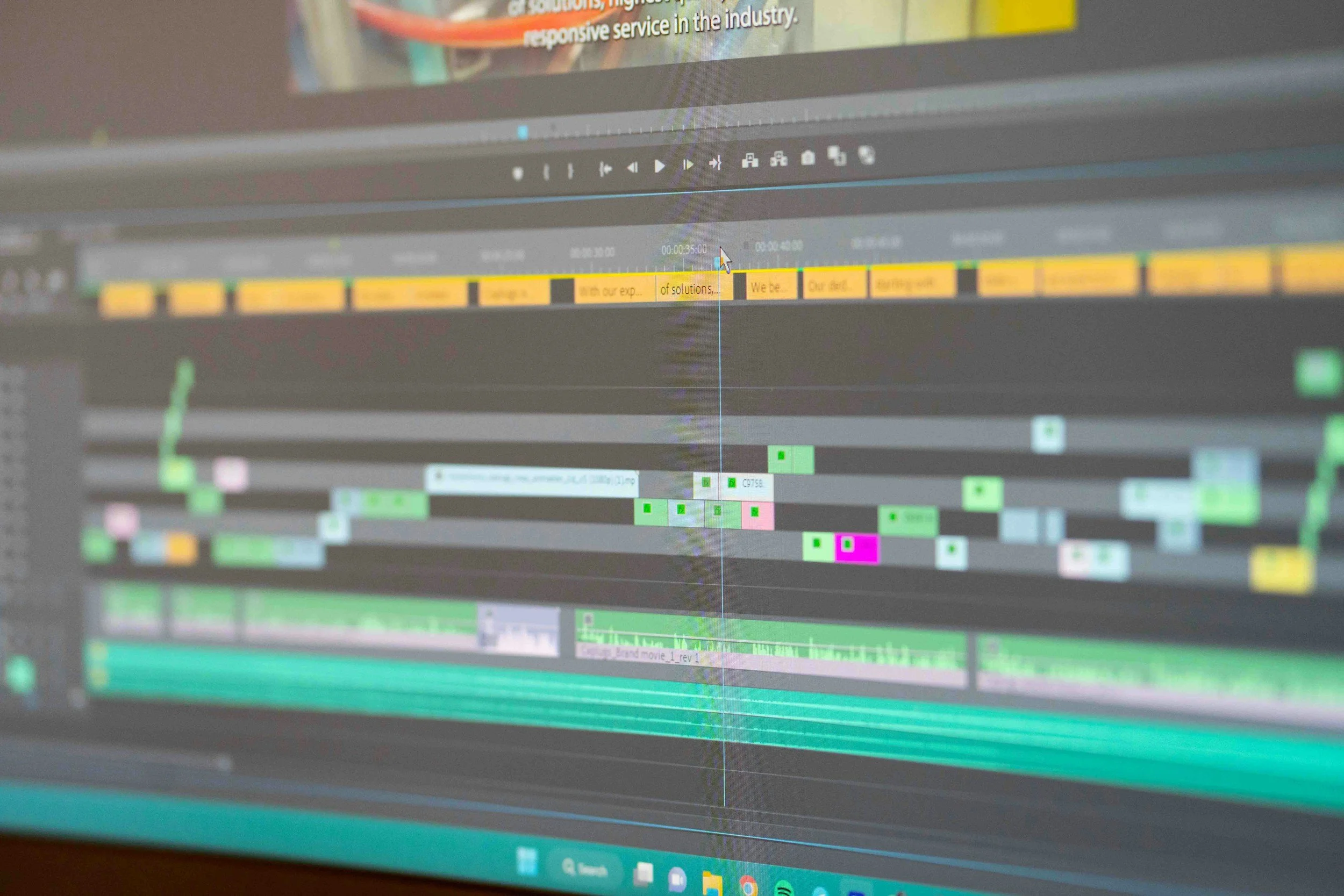Close-up of a computer screen displaying a video editing timeline with various colored clips and audio tracks.