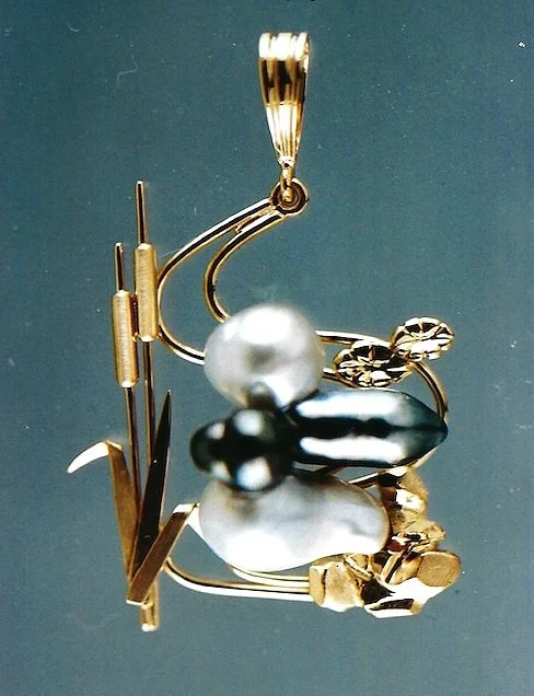 Decorative brooch featuring a large pearl, gold and silver elements, and abstract shapes.