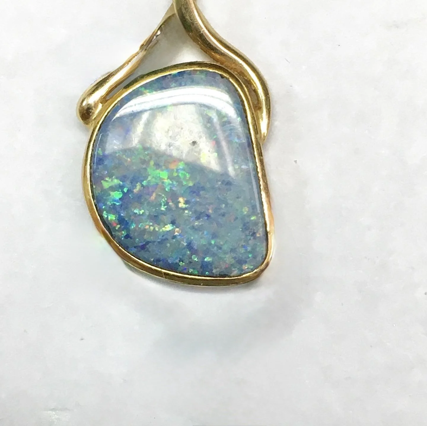 Our client came to us with a lovely piece: a beautiful, iridescent opal set in a very simple, standard gold frame with a dated setting and didn't reflect our client's personality.
