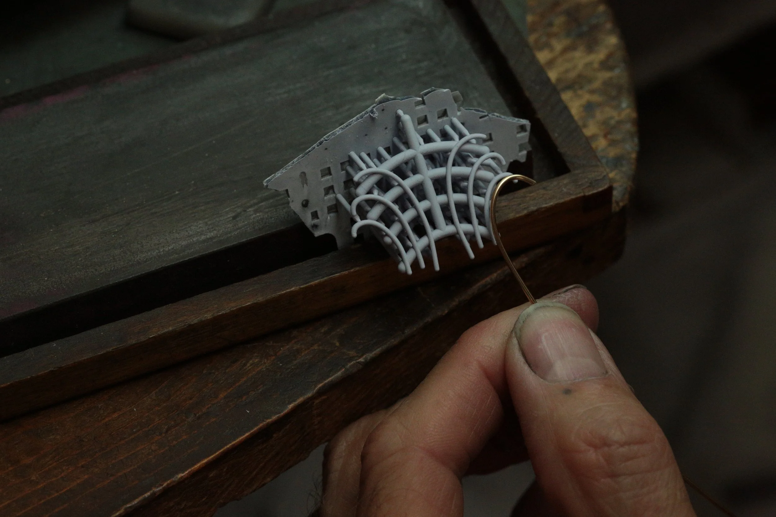 our master jeweler beginning the intricate wire work, carefully bending and shaping the foundation of the piece to match the precise curvature of the "JJ" design at Stark Jewelers in Sacramento.