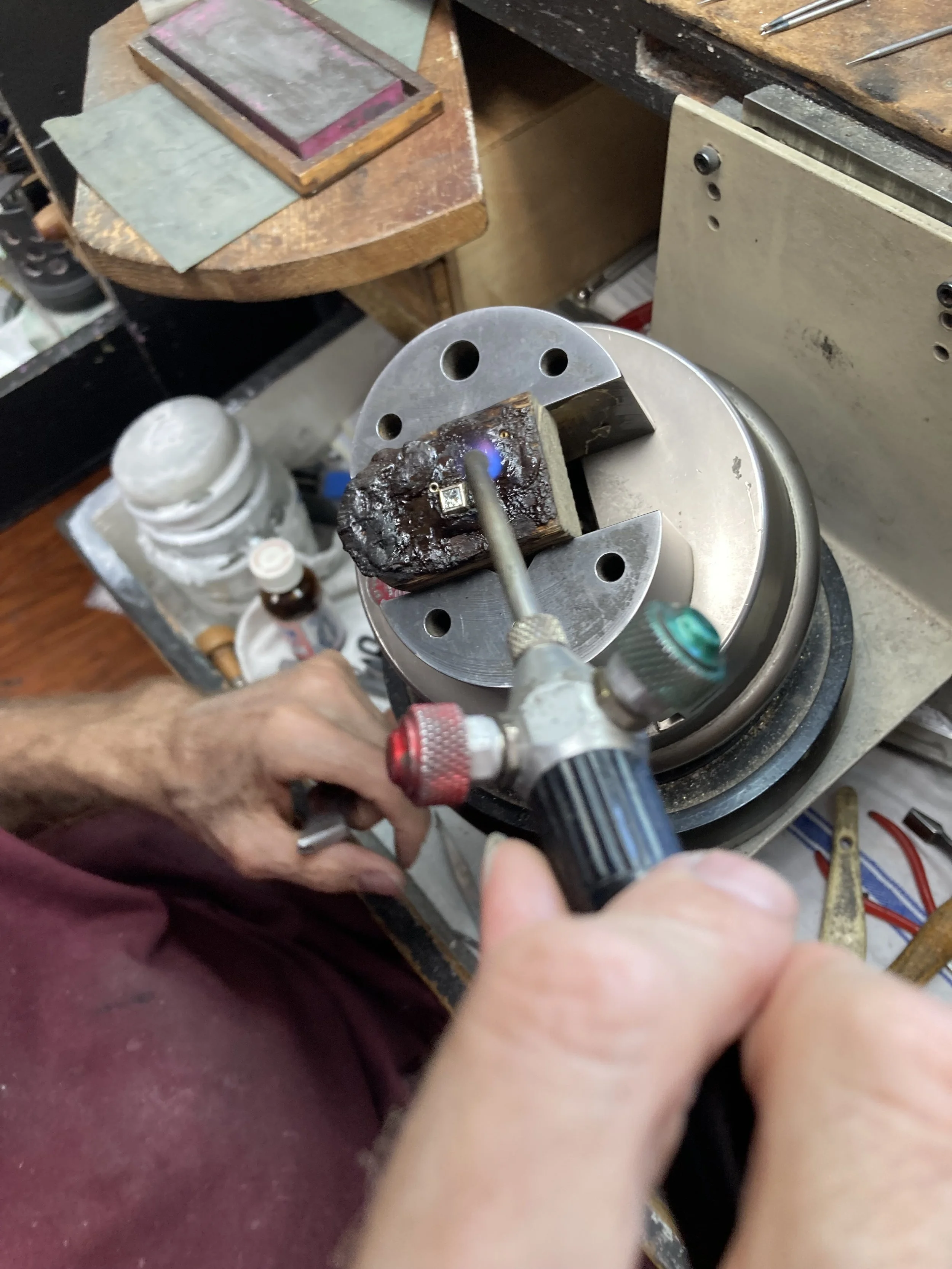 Our master jeweler applies intense torch heat to prepare the metal components for diamond setting in our studio in Arden Arcade.