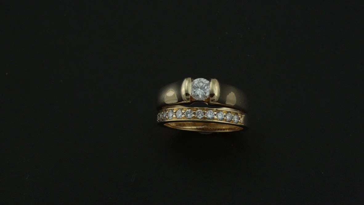 Gold ring with a row of small diamonds and a solitary larger diamond on a black background.
