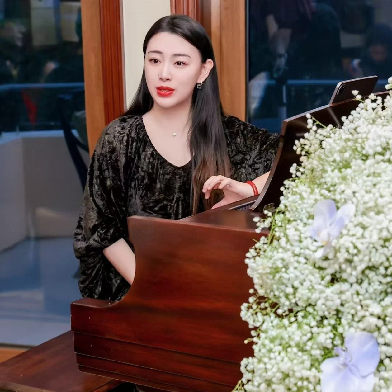 A lady with a black dress sitting in front of piano