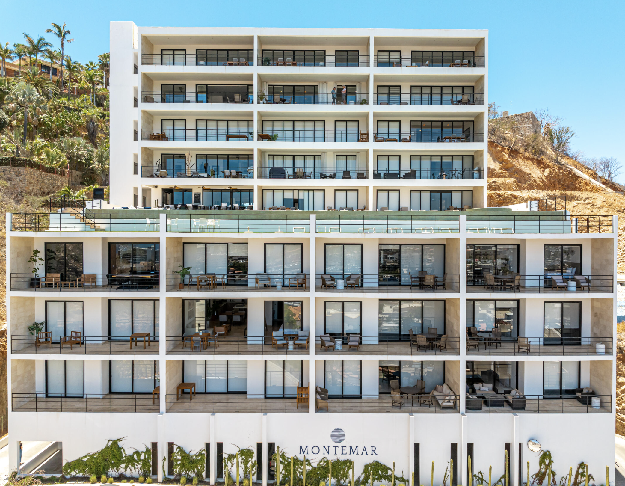 Exterior view of a multi-story hotel building with balconies and large glass windows.