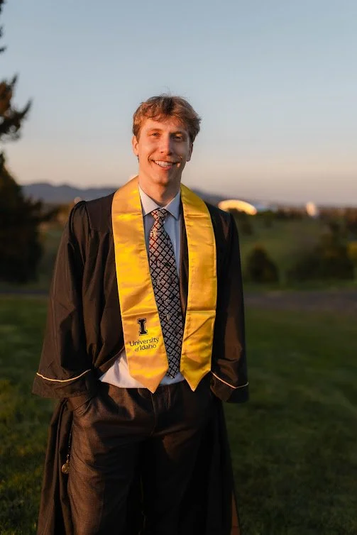 Senior portrait of young man in his cap & gown at sunset on the gold course, captured by LaFleur Photography.
