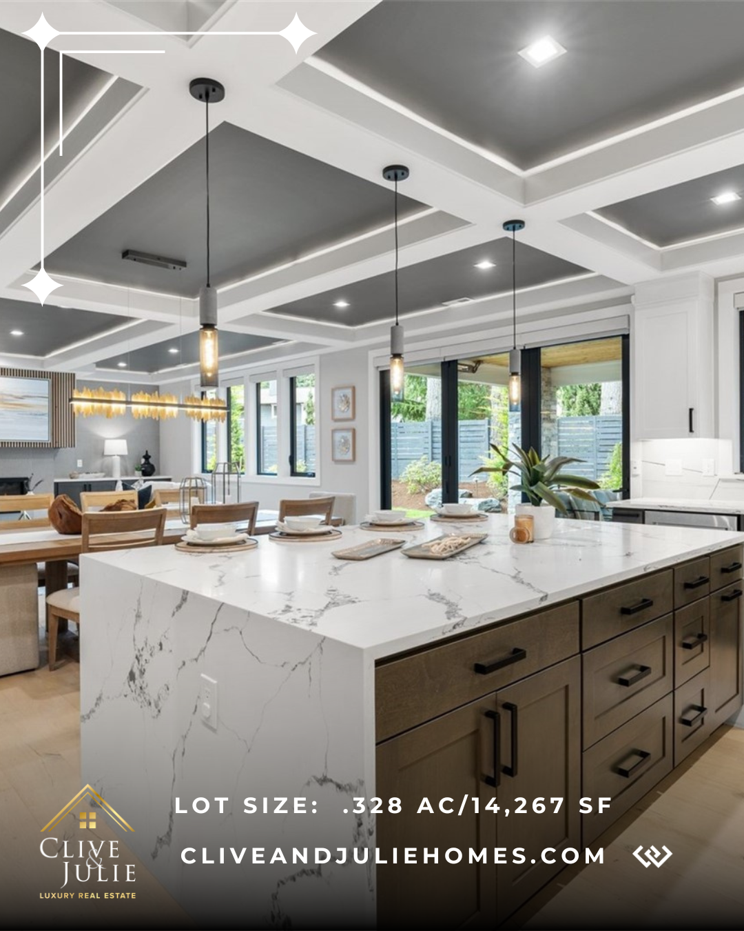 Modern kitchen with white marble countertops, black cabinets, and pendant lighting, open to dining and living areas with large windows and sliding doors to exterior yard.
