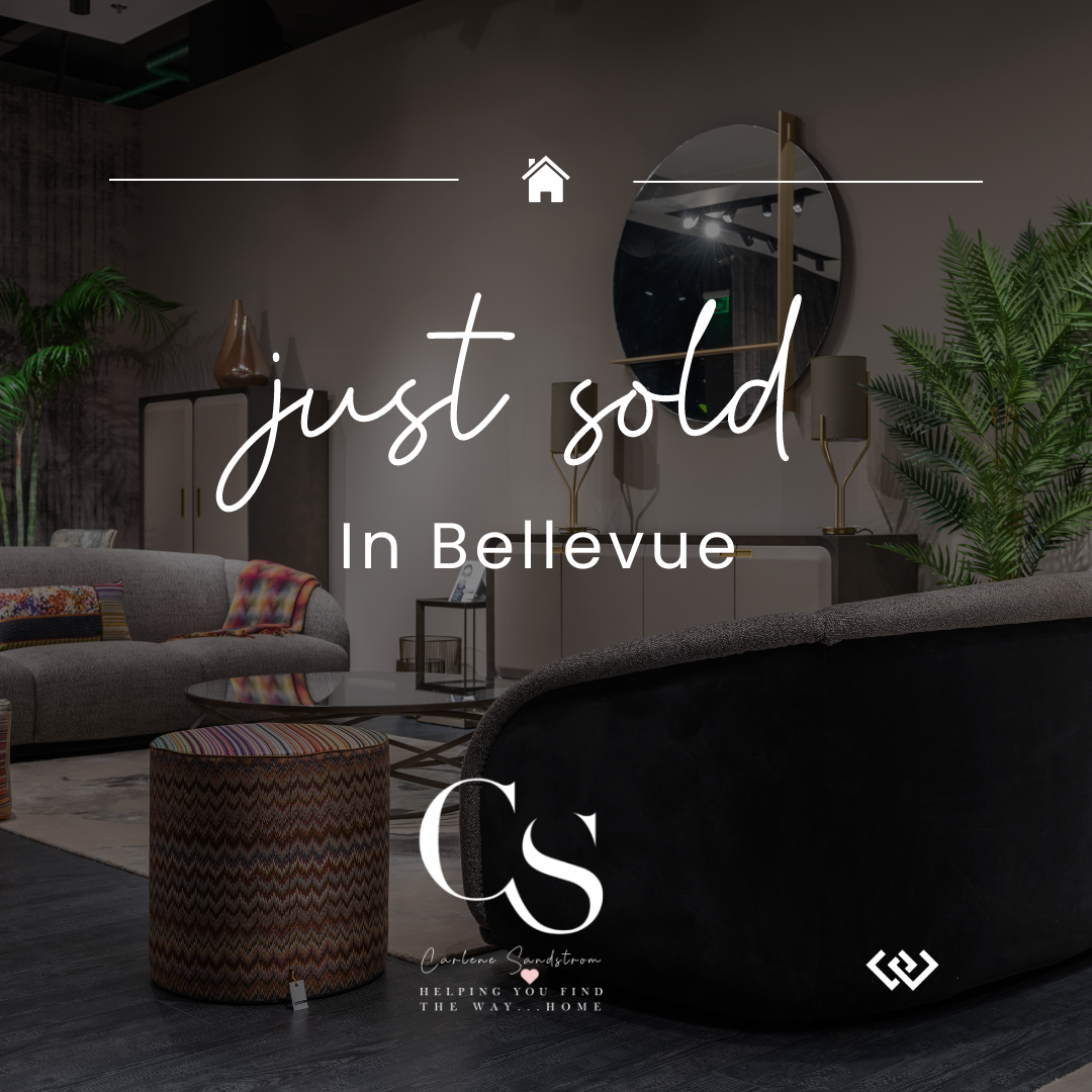 Interior of a modern living room with a beige sofa, a multicolored ottoman, a round mirror, and large green plants, with the overlay text 'just sold in Bellevue' and a logo at the bottom.