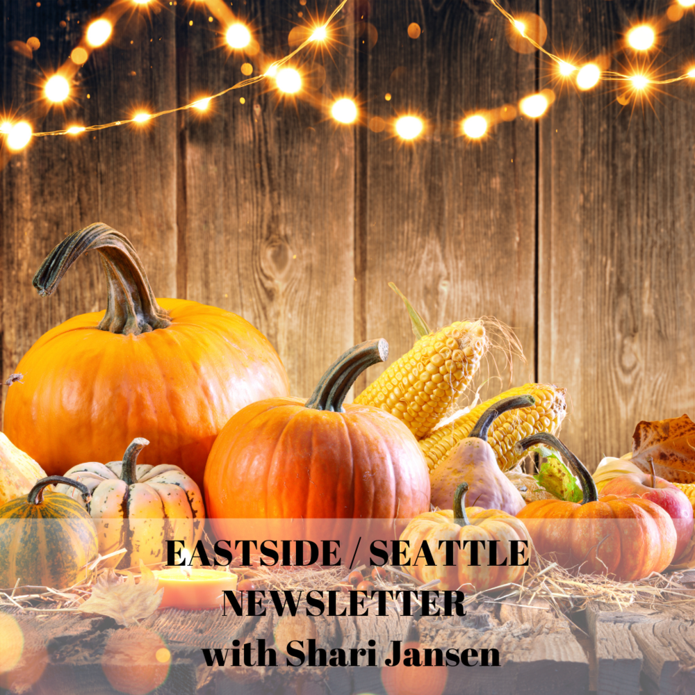 Autumn harvest display of pumpkins, corn, and gourds on a rustic wooden table with string lights above.