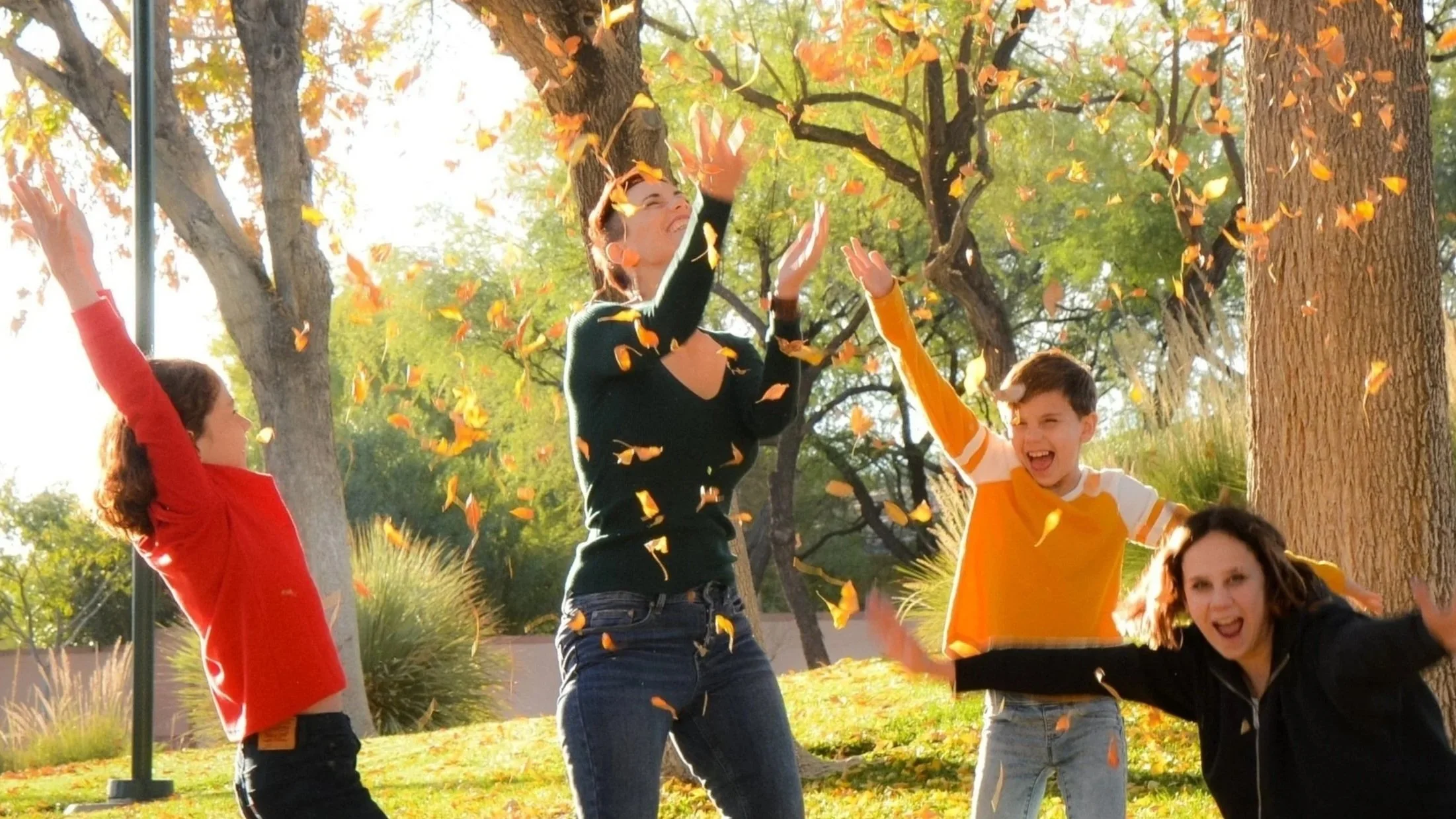 family throws up leaves in the park -stillpointherapy-female-therapist-las-vegas-mom-therapy-page