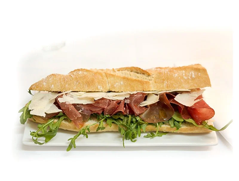 Een broodje met vlees, sla, tomaat en kaas op een wit bord.