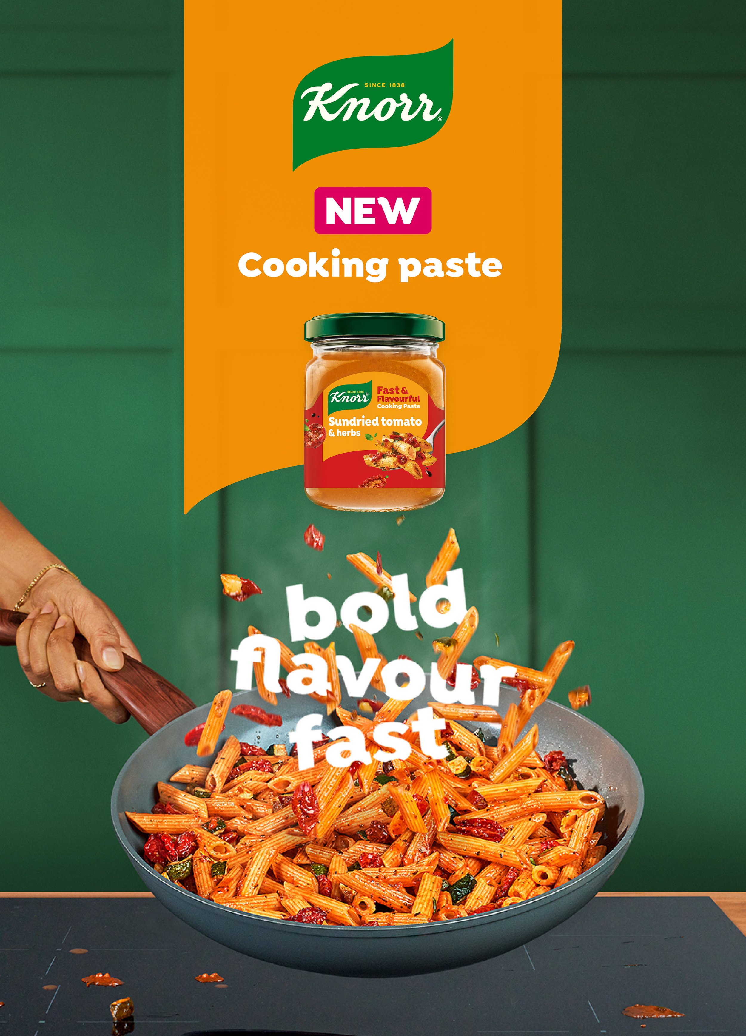 Immagine di una confezione di Knorr Cooking Paste, sapore di pomodoro sundried, posta sopra un piatto di pasta con pomodori secchi, erbe e salsa, mentre una mano utilizza una spatola di legno per mescolare.