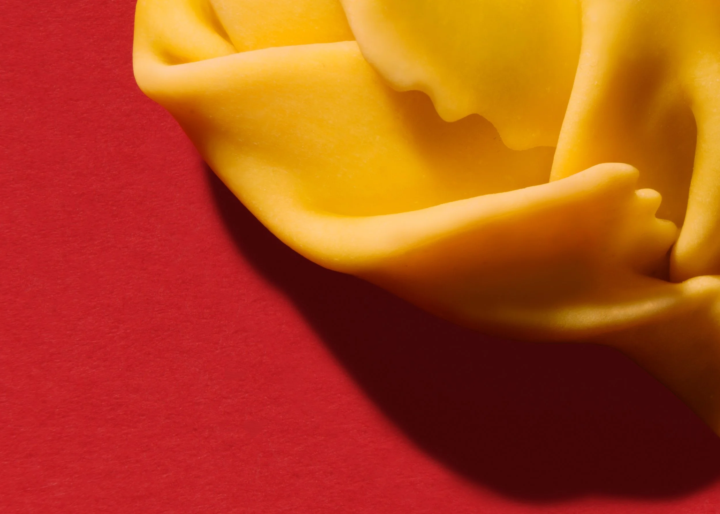 Primo piano di un pezzo di formaggio giallo su uno sfondo rosso.