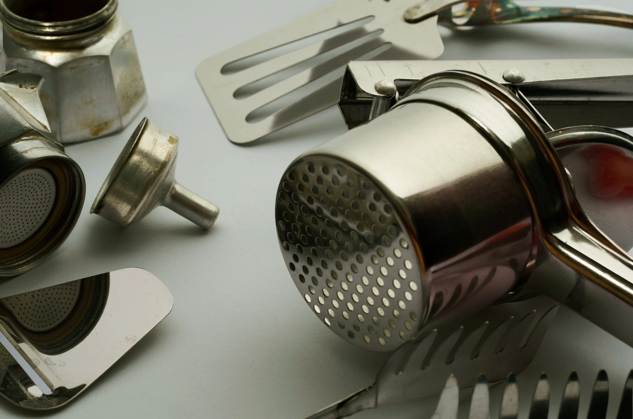 caffettiera-schiacciapatate-filtro-spatola-pomodoro-riflesso-pinza-pasta-metallo-astratto-acciaio-fotografo-food.jpg