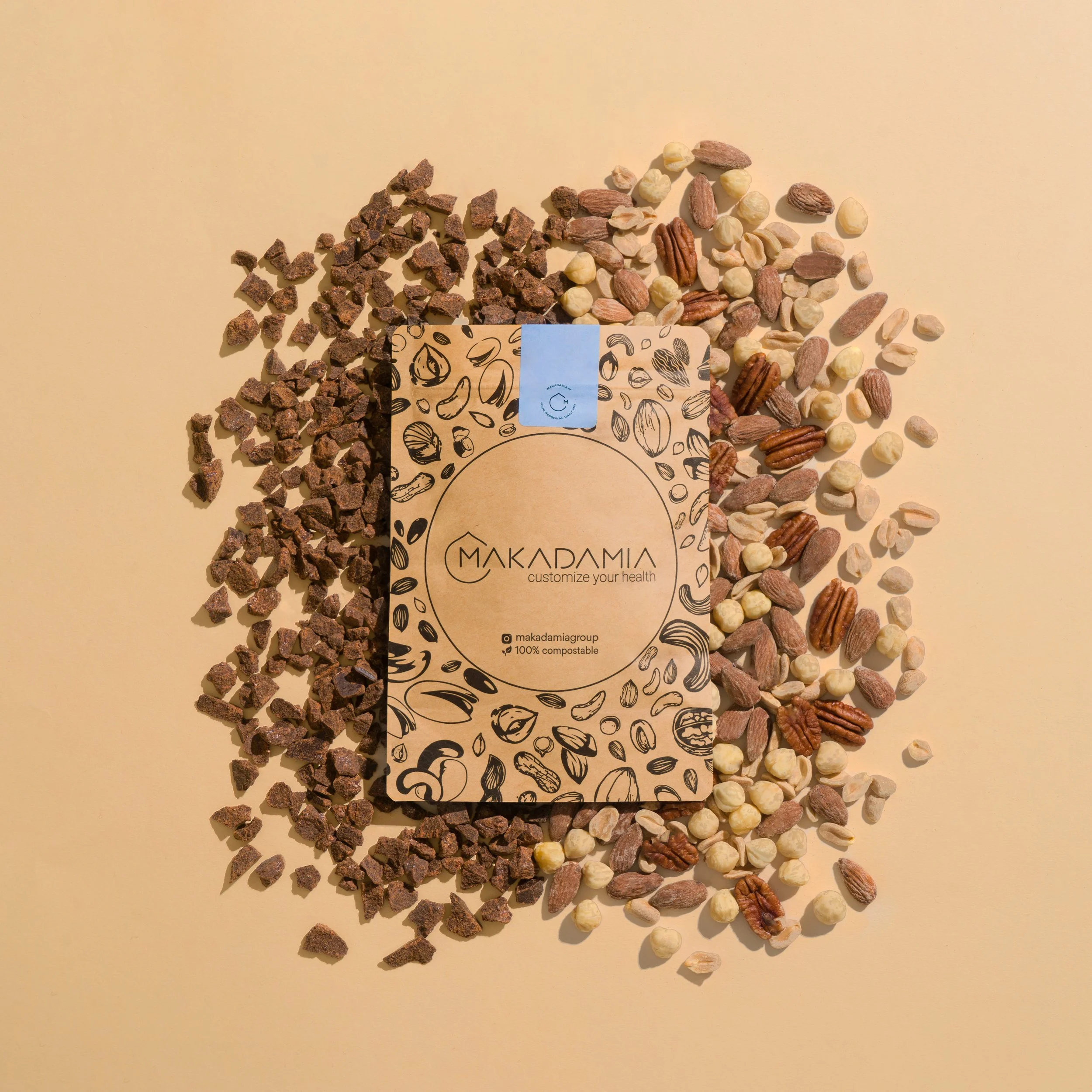 Disposizione di vari tipi di noci e semi su sfondo beige, con un biglietto con disegni di noci e semi e il testo 'Makadamiu Group, personalizza la tua salute, 100% compostabile'.
