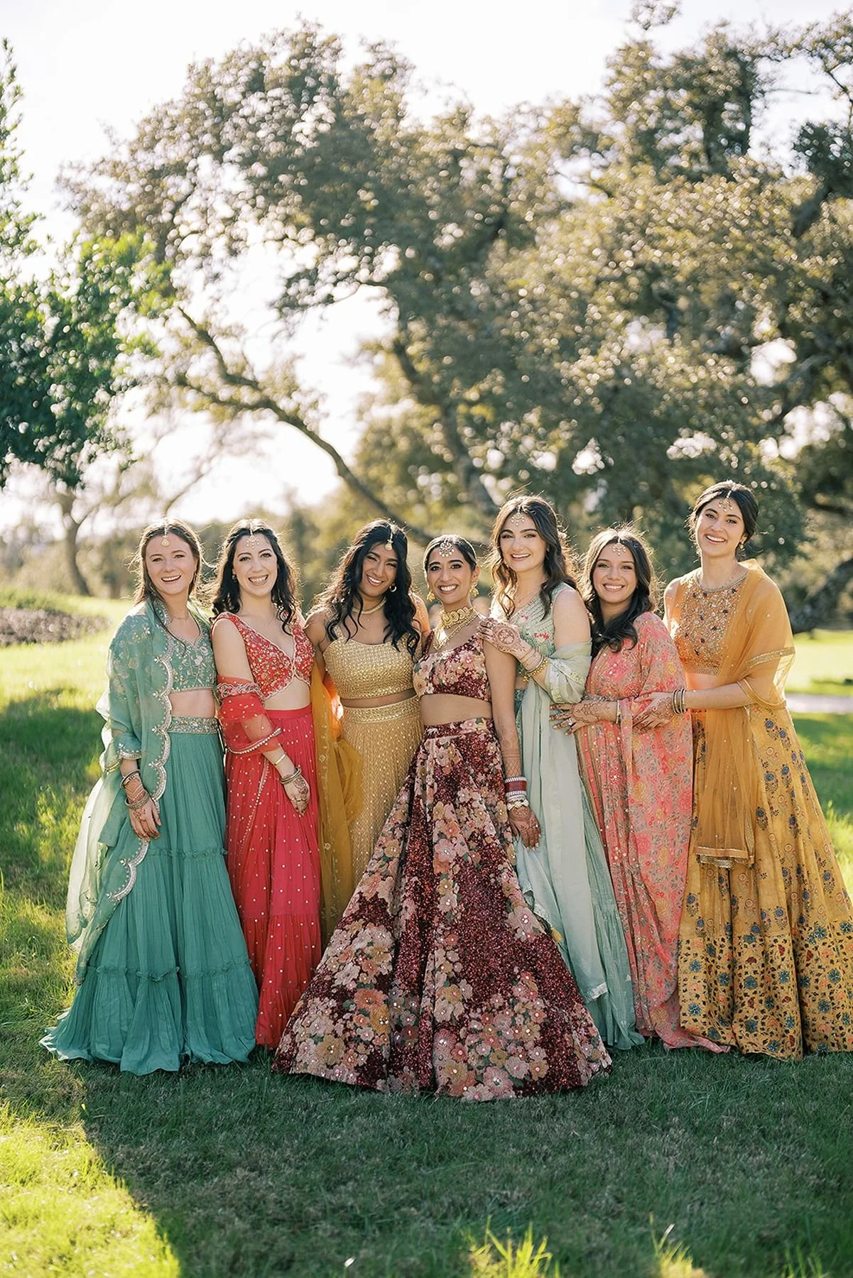 Mismatched colorful bridesmaid lenghas in turquoise, coral, mustard, pink, aqua and Indian bridal dress in red by sabyasachi