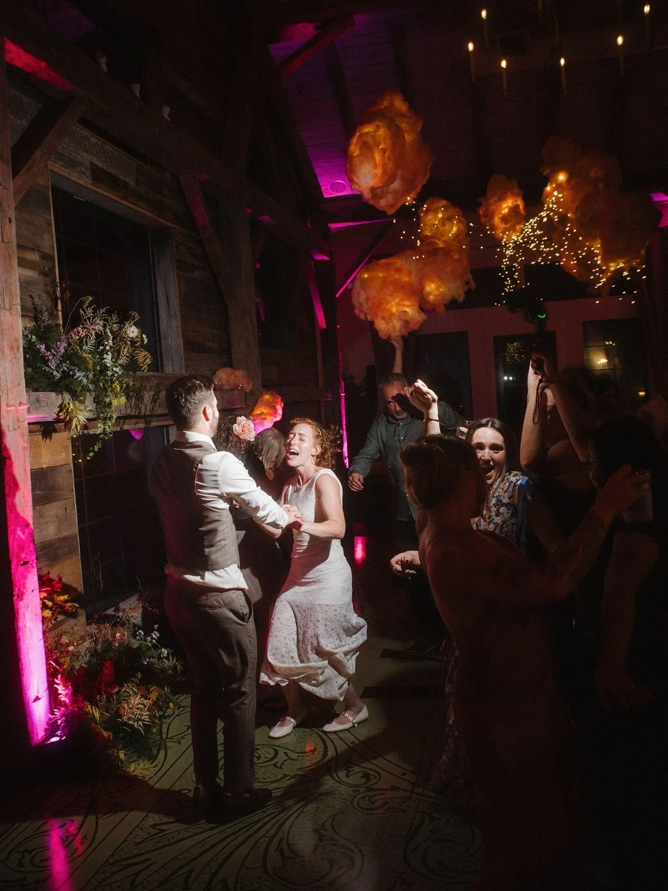 Night time dance floor with custom cloud installation above the dance floor, bride and groom holding hands, singing and dancing together by wedding planners epoch co