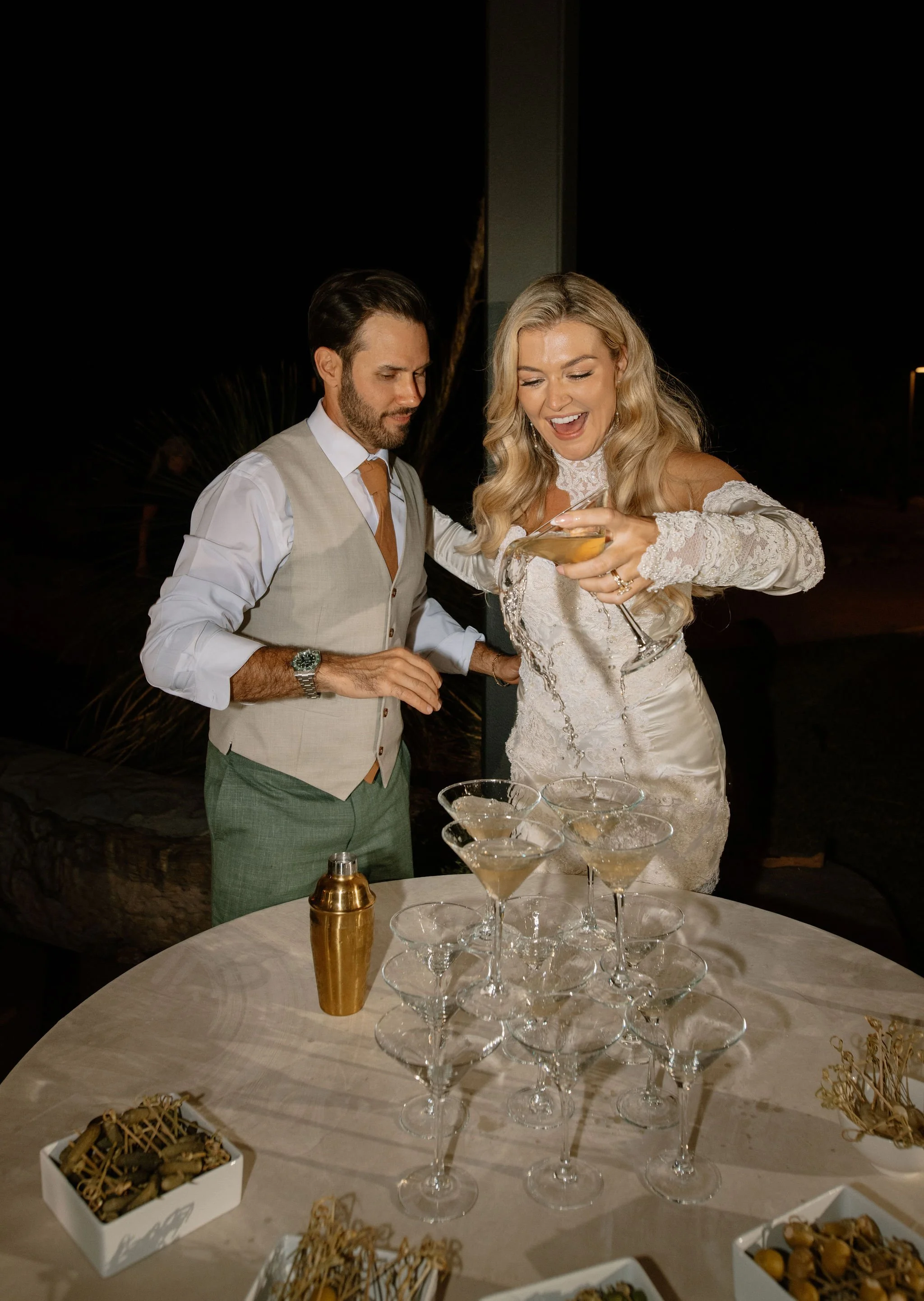 Couple pouring a martini tower together — bold, lighthearted twist on the classic champagne moment at a Gen Z wedding