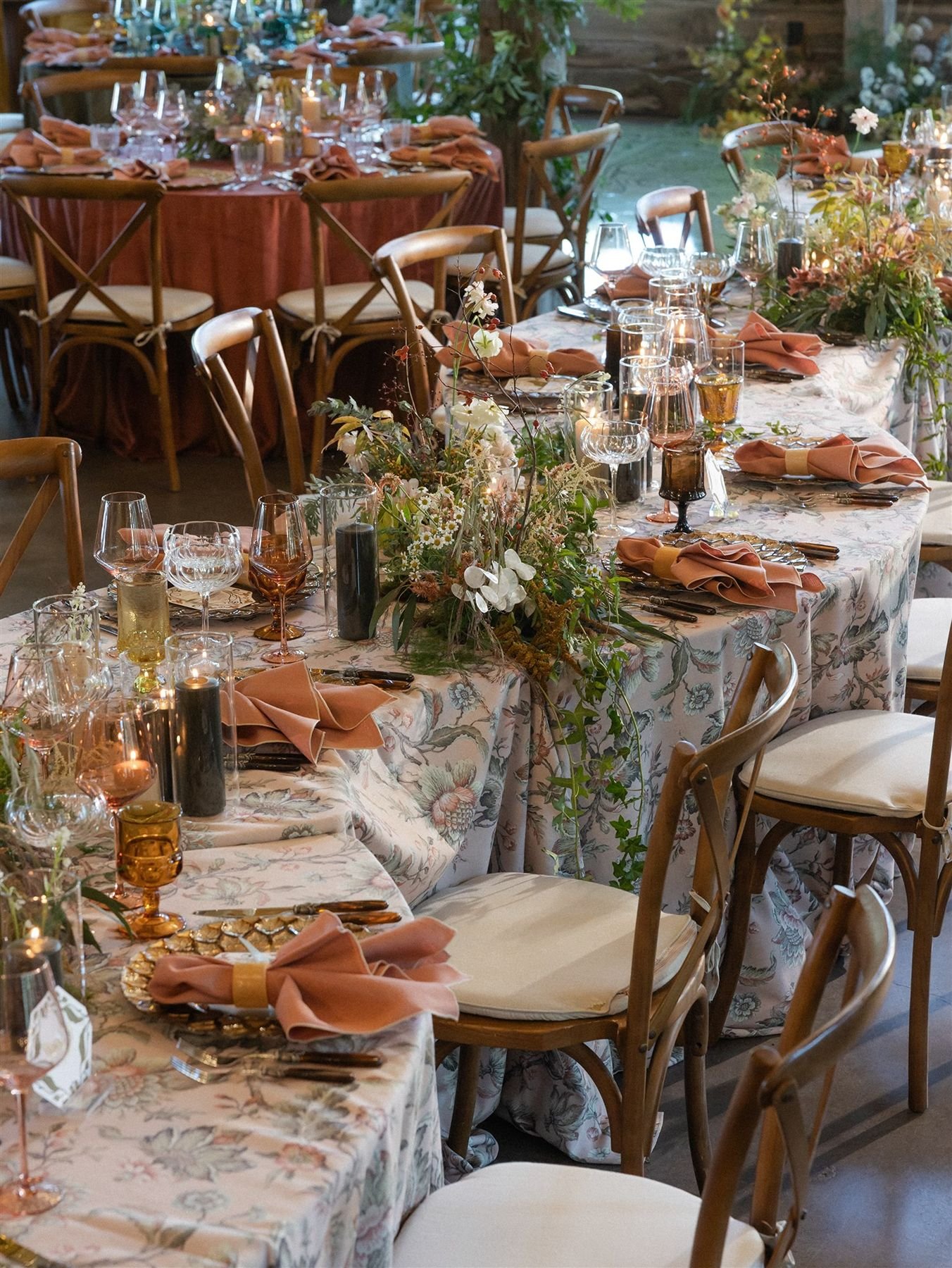 Floral art nouveau patterned linen on a serpentine table with woodland whimsical florals, colored stemware glasses, redwood napkins for a woodland romance lord of the rings wedding design houston wedding planners