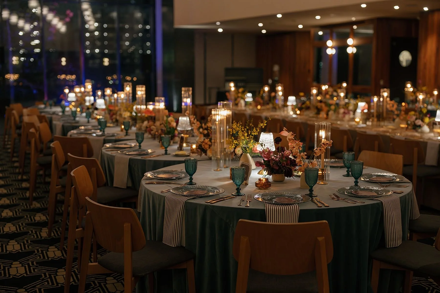caterpillar serpentine table design with blue velvet, table lamps, striped napkins and warm ambiance designed by Austin Texas wedding planners epoch co